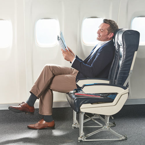 Man wearing compression socks while reading on airplane.